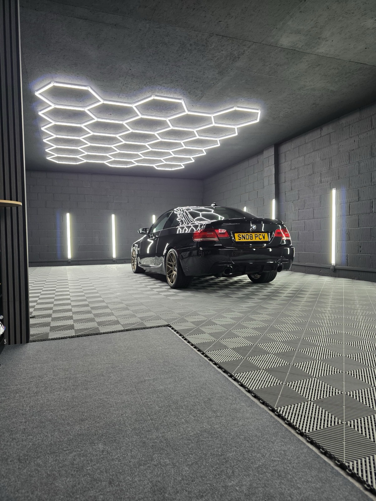 A freshly detailed black BMW glowing under M&M Detailing's hexagon studio lighting
